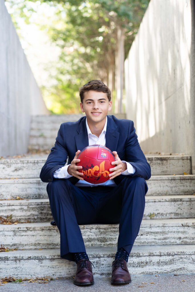 senior guy picture idea with soccer ball wearing a suit at Kimbell Art Museum in Fort Worth