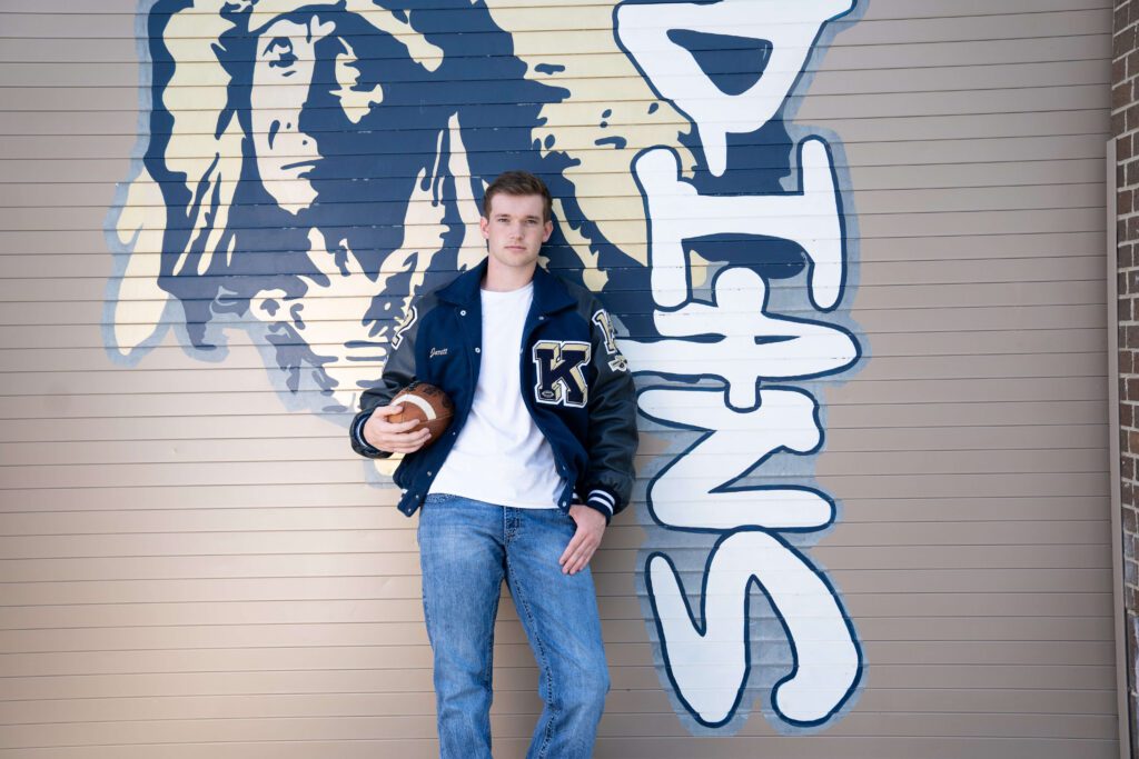 keller high school guy senior portrait with letterman jacket and football
